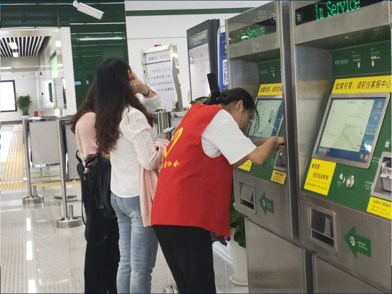 李岚作为地铁志愿者引导乘客出示健康码、核酸报告,帮助乘客购买车票