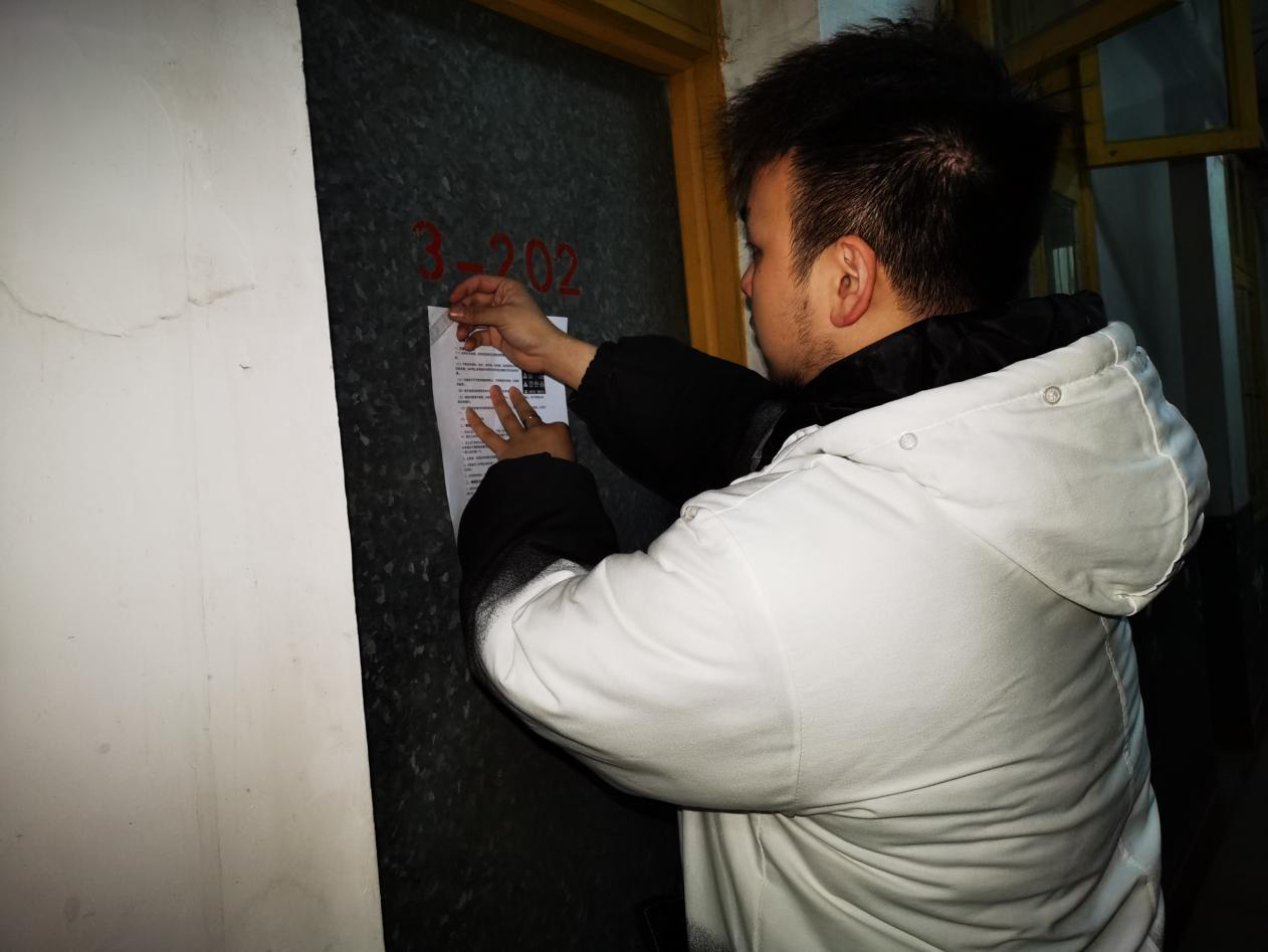 图四 研究生会副主席对无人的寝室进行“三防”宣传单的张贴